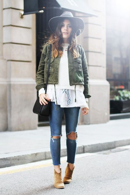 a white lace top, a white sweater, an olive green cropped jacket, blue ripped skinnies, ocher booties, a black hat and a black bag