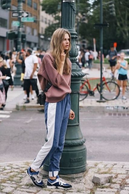 a casual sporty look with an oversized dusty pink sweatshirt, blue side-striped pants, matching trainers and a black bag