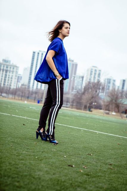 a sporty outfit with a bold blue top, black side-striped pants, black and blue shoes