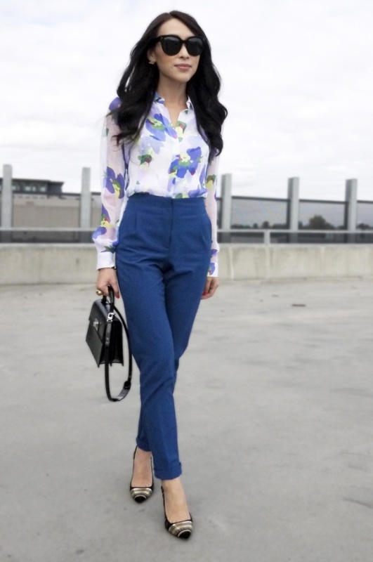 A bright work look with a blue floral print shirt, blue pants, heels and a black bag is a timeless idea