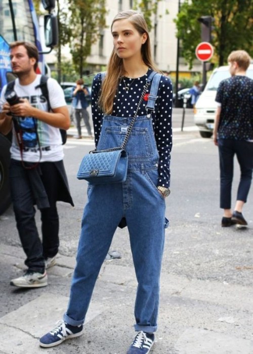 a navy and white polka dot top, a blue denim dungaree, a light blue bag and blue sneakers for spring