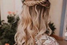 a beautiful boho wedding hairstyle with a fishtail braid halo, waves down and bold blooms and pale leaves tucked in