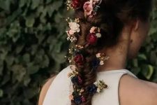 a beautiful thick and long fishtail braid with burgundy, pink and black blooms tucked in for a fall boho bride