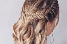 a boho half updo on medium hair, with a large fishtail braid on one side and waves down is a stylish solution