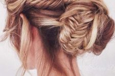 a messy and volumetric updo with fishtail braids and a low bun plus a messy volume on top