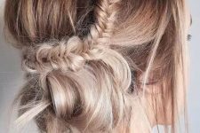 a messy updo with a side fishtail braid and a low bun plus a bump on top is a cool and catchy idea