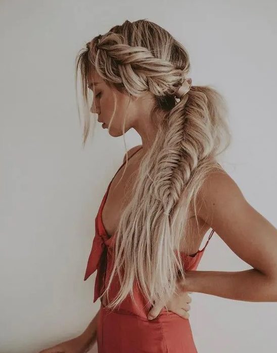 a side swept hairstyle of a dimensional and loose fishtail braid and some waves down and some locks down is wow