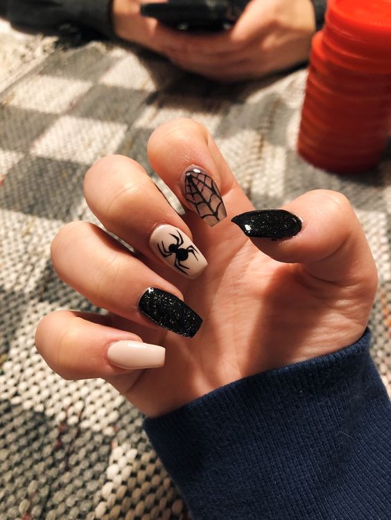 a creamy, clear and black glitter manicure with spiderwebs and spiders is a very refined solution for Halloween