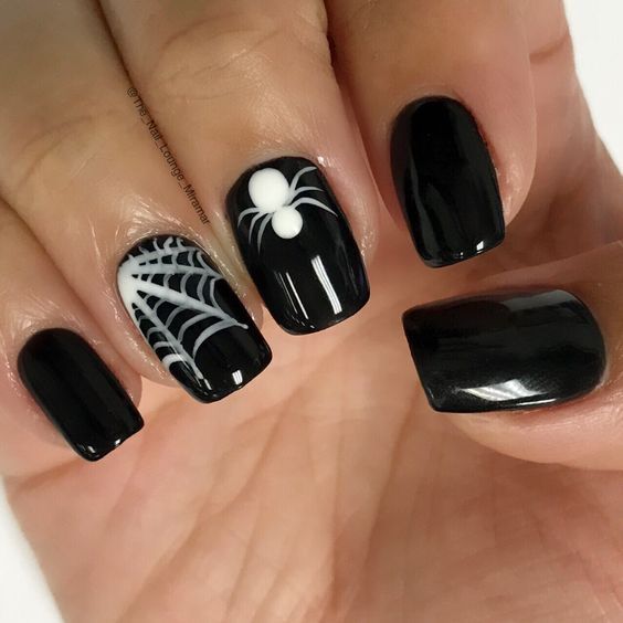 a glossy black manicure with a white spiderweb and a white spider is amazing for Halloween