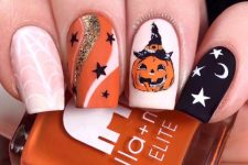a nude, white, orange and black nail with a pumpkin, stars, moons and spiderwebs for Halloween