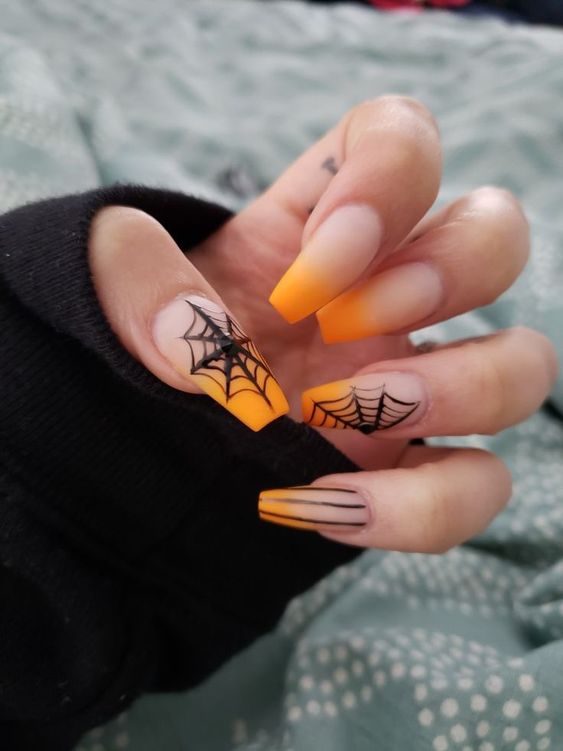 nude and orange nails with spiderwebs and rhinestones for a chic and bright Halloween look