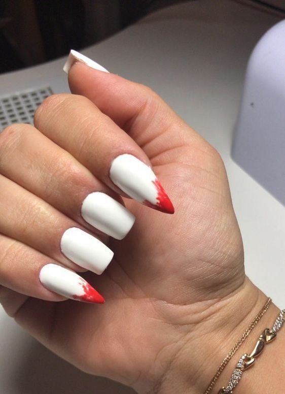 white nails with shapr ones with blood show off vampire teeth, which is a very bold and edgy solution