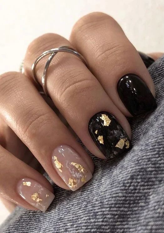 a cool and shiny NYE manicure with nude and black nails and gold foil is adorable for parties