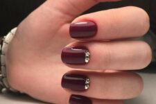 a glossy burgundy manicure with shiny gold embellishments is a lovely refined option to rock