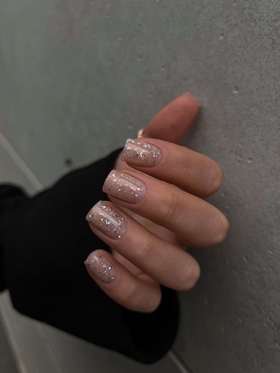 a nude manicure with colorful sparkles is a lovely idea for NYE and will look fine after that, too