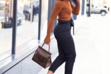 black high waisted cropped pants, a rust-colored top with long sleeves, nude heels, a black hat and a taupe bag – everything is accented