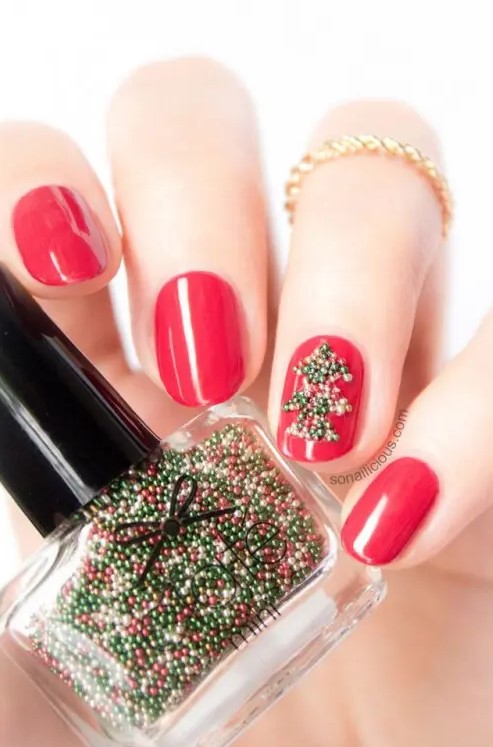 Bold red nails with an accent nail that shows off a green bead tree are very creative, bold and stylish for a color loving girl