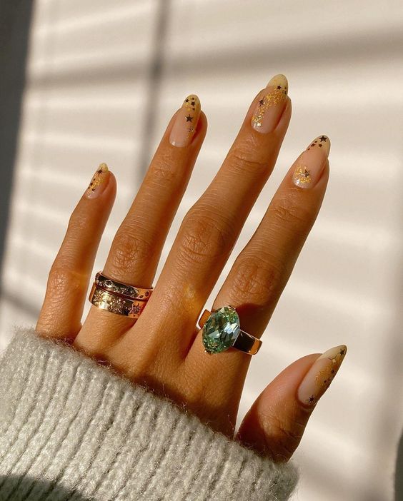 nude nails accented with gold stars and sparkles are amazing for Christmas or NYE parties