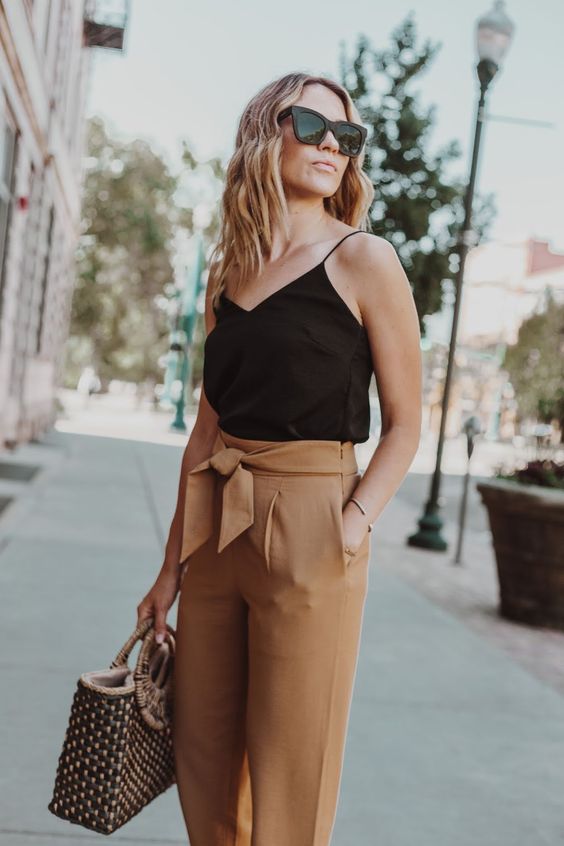 a black spaghetti strap top, rust-colored paper bag pants and a woven bag for a summer look