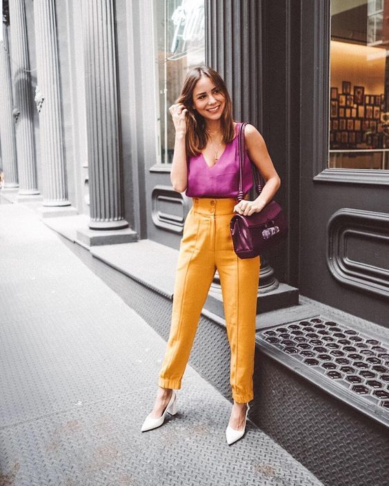 a hot pink sleeveless top with a V neckline, yellow pants, white shoes and a purple bag for a splash of color