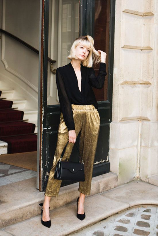 a black semi sheer blouse, gold metallic pants, black shoes and a black bag are a lovely combo for NYE