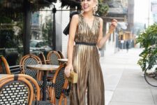 a gold metallic jumpsuit with a V-neckline and wide straps, black strappy shoes and a gold clutch for NYE