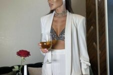a white pantsuit with an oversized blazer, a silver sequin bra, statement jewelry are a luxurious outfit for NYE
