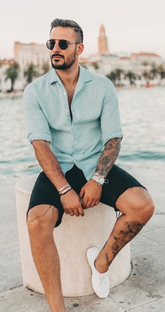 a blue linen shirt with rolled up sleeves and black denim shorts are a simple and very cool look for a vacation
