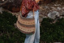a burgundy floral oversized shirt, blue jeans, burgundy strappy heels and an embroidered tote
