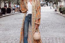 a stylish boho look with a white tee, blue jeans, yellow slippers, a woven bag and a floral print kimono