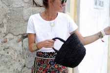 a white tee, a colorful floral mini skirt, a black straw bag and statement accessories