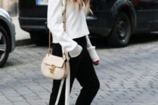 a contrasting look with a white sweatshirt, black side stripe pants, white sneakers and a neutral bag