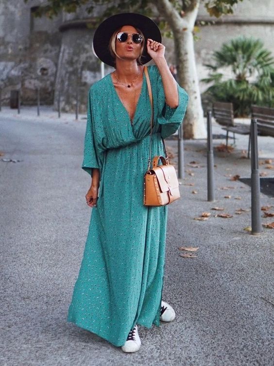 a green wrap printed maxi dress, layered necklaces, white sneakers, a brown bag and a black hat
