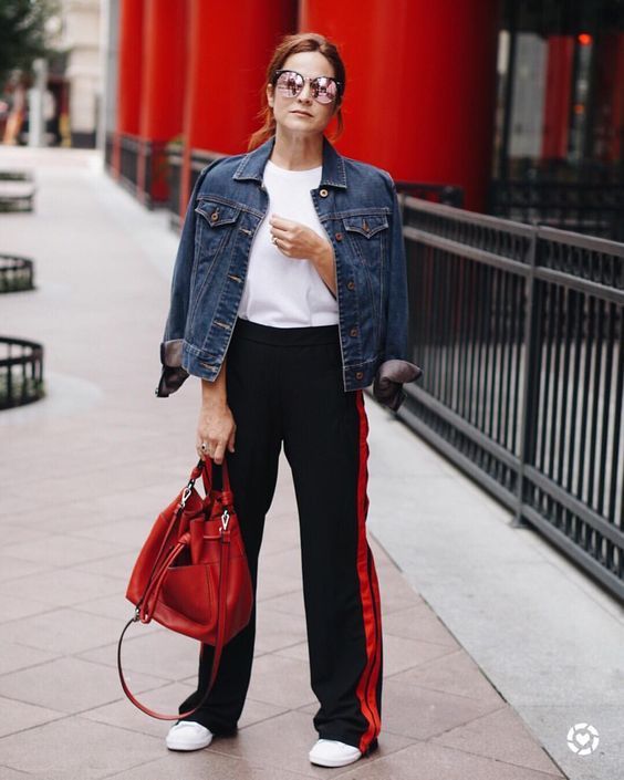 a simple and stylish look with a white tee, black side stripe pants, white sneakers, a blue denim jacket and a red bag
