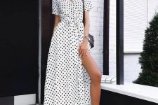 a white and black wrap polka dot maxi dress, white sneakers, a black bag for a monochromatic look