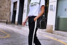 an everyday look with a white printed tee, black side stripe pants, white sneakers, a black bag