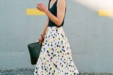 a bright summer work outfit with a black top, a colorful polka dot midi, blue lace up flats and a clutch