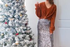 a Christmas party look with a rust-colored knotted sweater, a silver sequin midi skirt, black ankle strap shoes