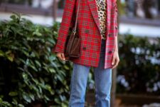 a bright Christmas look with a leopard print turtleneck, blue jeans, red strappy heels, a bold red plaid blazer and a brown bag