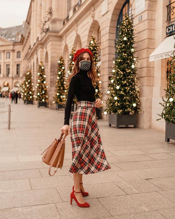 a retro chic Christmas outfit with a black turtleneck, a plaid midi skirt, red shoes, a red beret and a beige bag