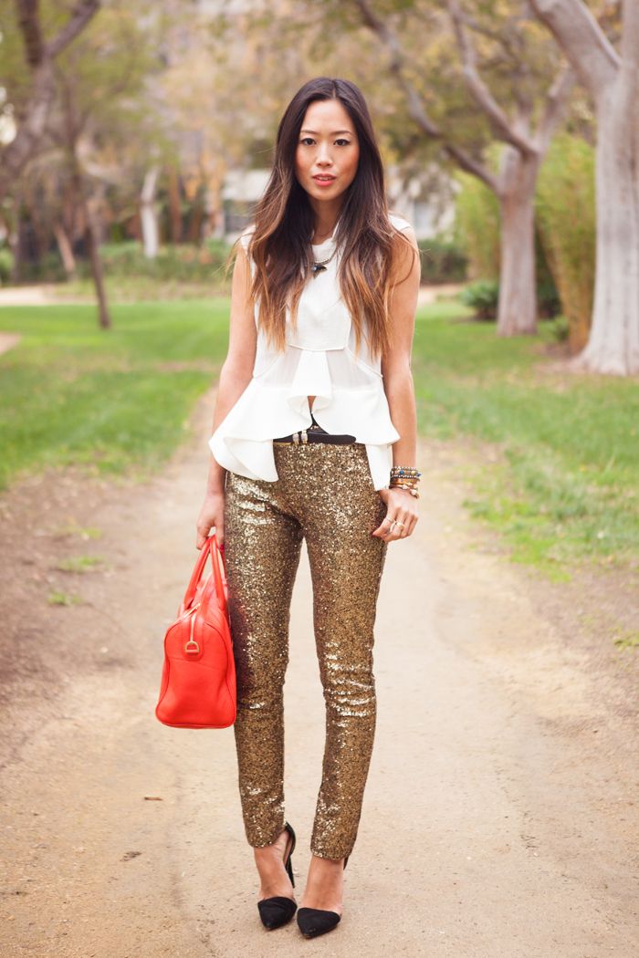 a refined Christmas party outfit with a white sleeveless peplum top, gold sequin trousers, black shoes and a red bag