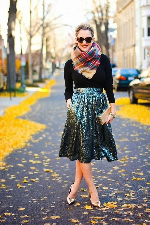 a stylish Christmassy outfit with a black turtleneck, a green sequin midi skirt, gold shoes, a plaid scarf and a gold box clutch