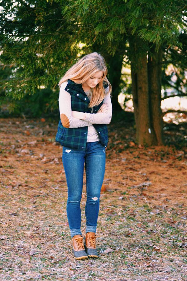 a relaxed Christmas outfit with a neutral top, blue jeans, a blue and green plaid quilted vest, hiker boots