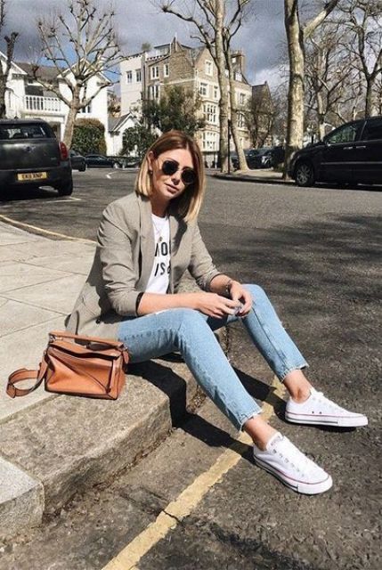 a spring look with blue skinnies, white sneakers, a printed tee, a neutral blazer, a brown bag and sunglasses