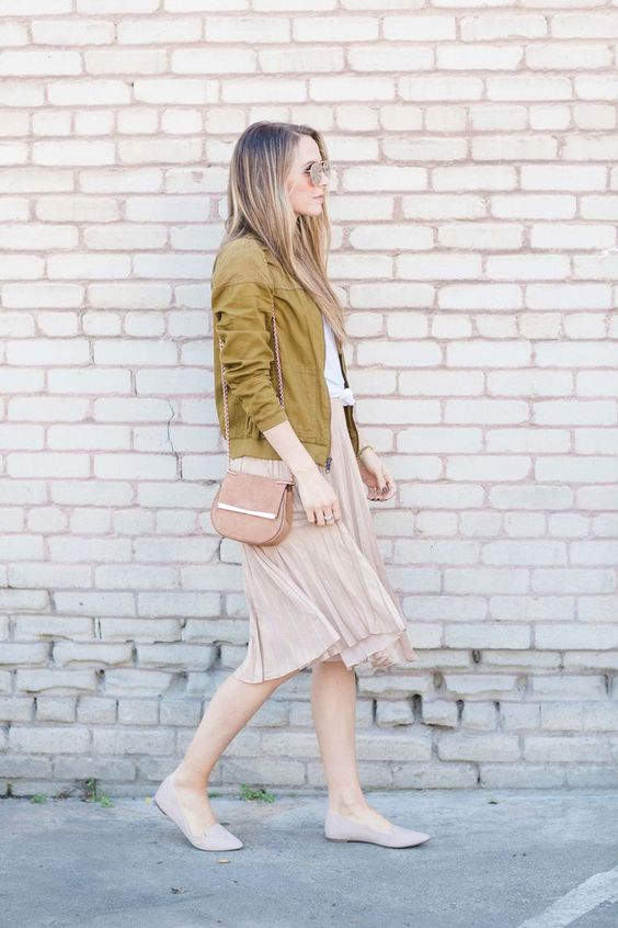 a white tee, a blush pelated skirt, nude flats, a pink bag and a mustard-colored bomber jacket