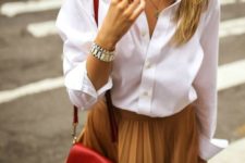 a white oversized shirt, a mustard pleated midi skirt, a red crossbody and statement earrings