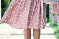a white top, a pink polka dot midi skirt, a brown belt, pink shoes and a grey bag