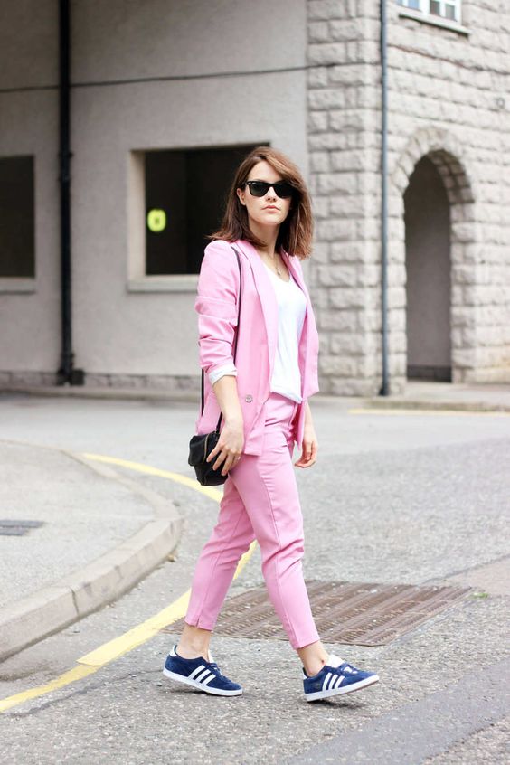 a pink pantsuit, navy sneakers, a black bag and a white top for a brigth casual summer work look