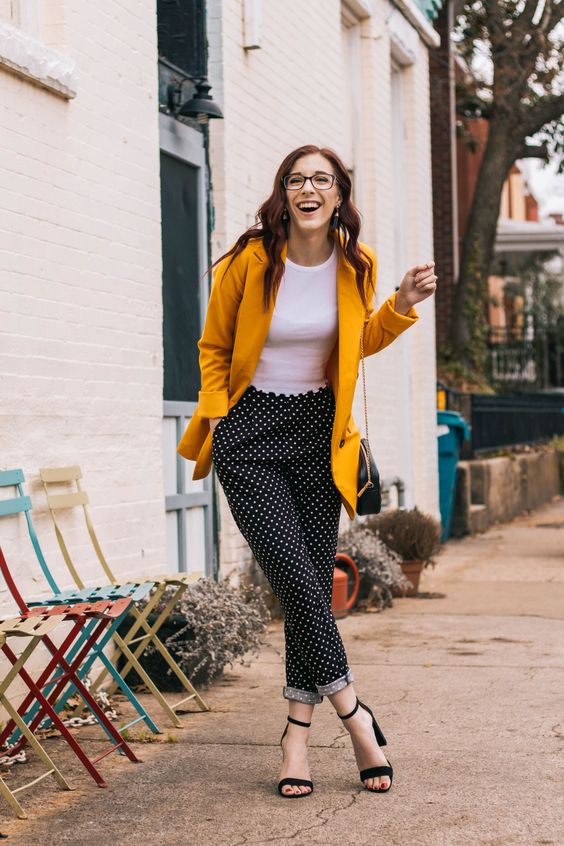 a summer work outfit with a white top, polka dot pants, a marigold blazer, black shoes and a black bag