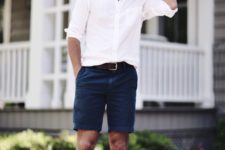 a white long sleeve cuffed shirt, navy shorts, brown shoes and a hat for vacation